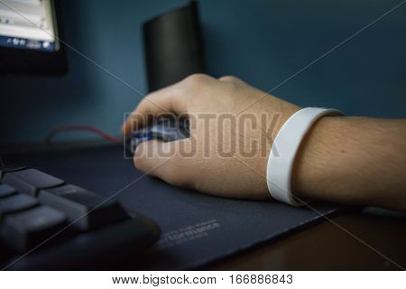 Male hand with bracelet holding computer mouse