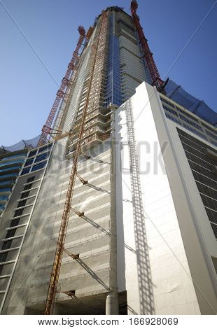 Building with cranes under construction shot from ground level