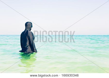young woman in burkini swimming in the sea, persian gulf, jumeirah beach in dubai