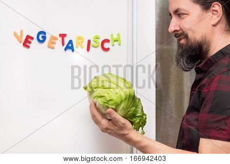 man holding a fresh salad fridge with german word vegetarisch which means vegetarian healthy nutrition