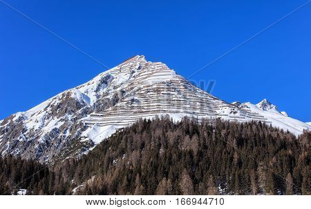 Summit of Schiahorn mountain with snow fences for avalanche control, as seen from the town of Davos in the Swiss canton of Graubunden in wintertime.