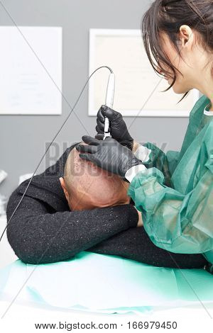 Cosmetologist making permanent makeup on man's skin head
