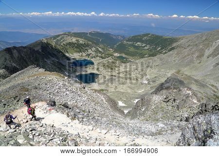RILA MOUNTAINS, BULGARIA - JULY 22, 2015: Panoramic view from Mousala Peak with hikers in the foreground