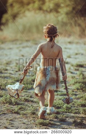 Angry Caveman, Manly Boy With Stone Axe And Animal Skull. Prehistoric Tribal Boy Outdoors On Nature.