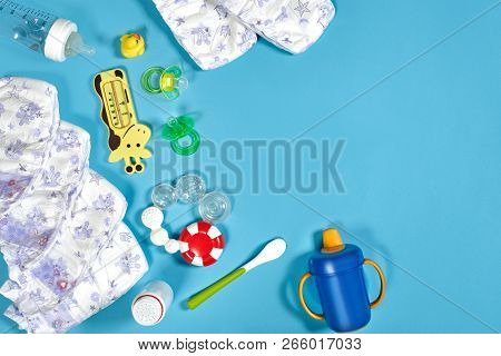 Babies Goods: Cloth Diaper, Baby Powder, Nibbler, Cream, Teether, Soother, Baby Toy On Blue Backgrou