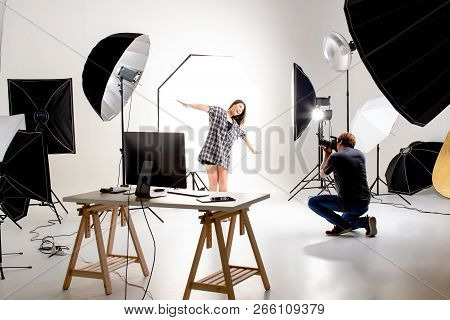 Photographer And Model Working In Modern Lighting Studio With Many Kinds Of Flash And Accessories.