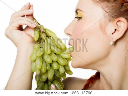 Beautiful Redhead Woman Licks Grapes. Concept Of Healthy Eating