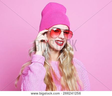 Stylish  fashion portrait of trendy casual young woman in pink pulover and  hat,  posing over pink background. Hipster style.