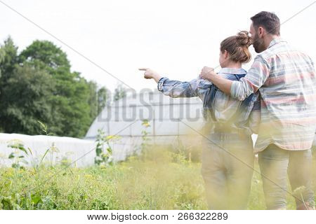 Rear photo of a loving husband and wife farmers looking locing over their beautiful farm
