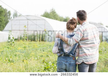 Rear photo of a loving husband and wife farmers looking locing over their beautiful farm