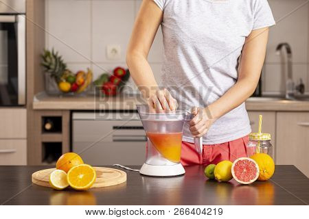 Detail Of Female Hands Holding A Grapefruit Half And Making A Freshly Squeezed Mixed Citrus Fruit Wi