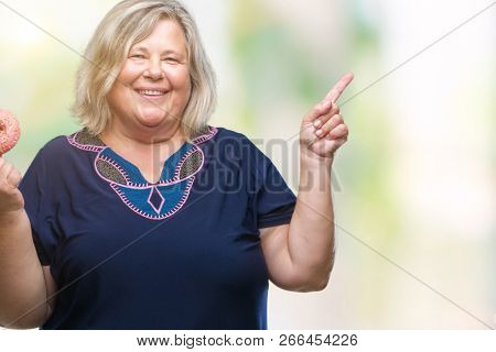 Senior plus size caucasian woman eating sugar donut over isolated background very happy pointing with hand and finger to the side