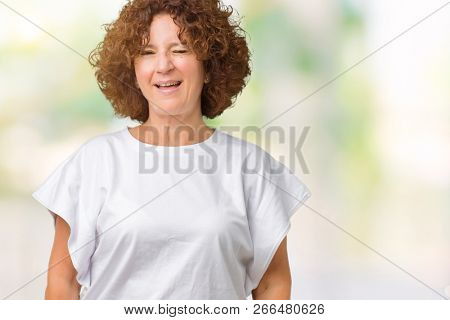Beautiful middle ager senior woman wearing white t-shirt over isolated background winking looking at the camera with sexy expression, cheerful and happy face.