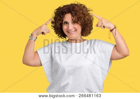 Beautiful middle ager senior woman wearing white t-shirt over isolated background Smiling pointing to head with both hands finger, great idea or thought, good memory