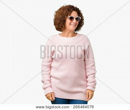 Beautiful middle ager senior woman wearing pink sweater and sunglasses over isolated background looking away to side with smile on face, natural expression. Laughing confident.