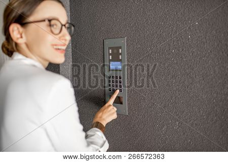Young Business Woman In White Suit Entering Code On The Intercom Keyboard Of The Residential Modern 