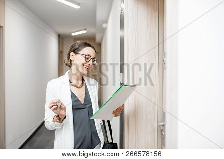 Portrait Of An Excited Woman With Key And Documents Standing Near The Dooor Of The New Apartment In 