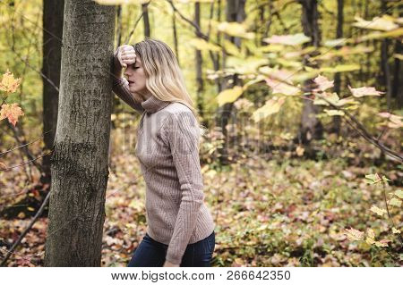 A Sad Woman In Park During Autumn Weather Hiding Face In Hand, Feeling Terrible Depressed.