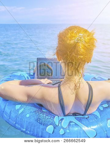 A Young Woman Is Floating On The Sea In A Swimming Circle. A Girl Is Relaxing On The Sea On The Infl