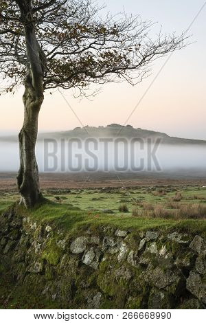 Stunning Foggy Sunrise Landscape Over The Tors In Dartmoor Revealing Peaks Through The Mist