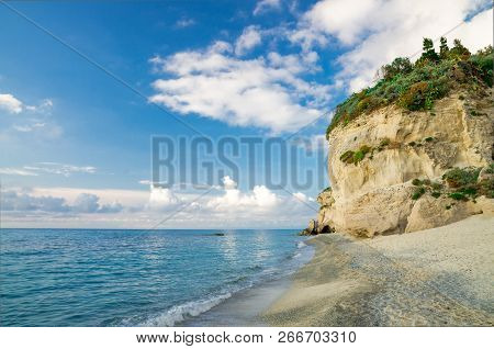 Rock With Greenery Near Sandy Beach Shore Coastline Of Tyrrhenian Sea With Blue Sky And White Clouds