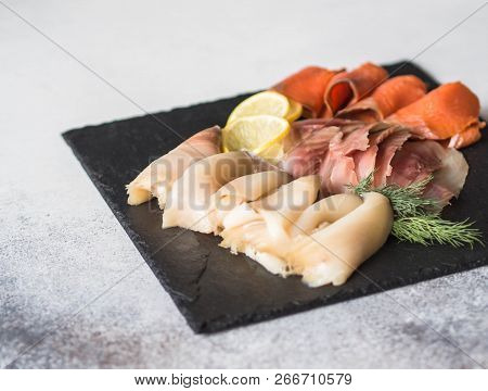 Slices Of Various Salted Fish - Salmon, Muksun, Oily Fish On A Black Slate Board On A Gray Backgroun