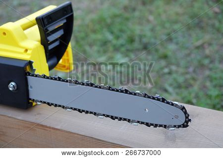 Electric Saw On Brown Wooden Balk Ready For Work Outdoors Closeup View