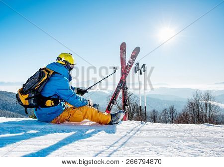 Rearview Shot Of A Skier Sitting On The Snow On Top Of The Mountain Taking Selfies With His Action C