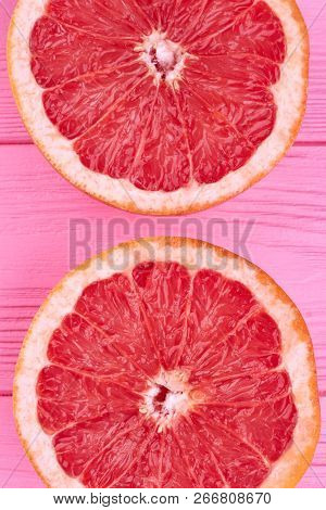 Sliced Halves Of Fresh Grapefruit. Ripe Delicious Grapefruit Cutted On Two Pieces On Pink Wood Close