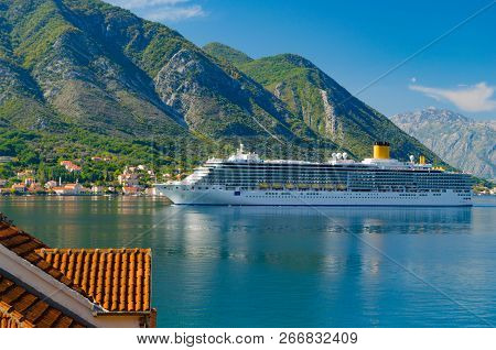 Large Tourist Ship Swam In A Bay Of Adriatic Sailing Past Small Town.the Background Of The Mountains