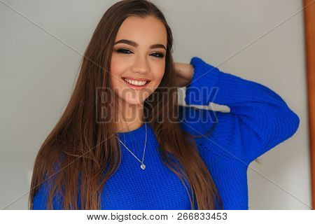 Portrait Of The Young Beautiful Smiling Woman Inside. Girl In Bkue Sweater. Fashion Makeup
