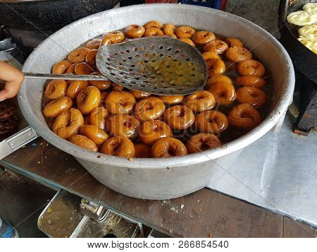 Fried Food Vada Dipped In Sweet Syrup In A Big Aluminium Container