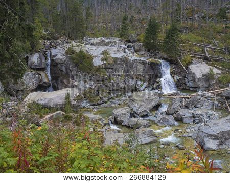 Waterfall Cascade On Wild River Stream Studeny Potok With Boulders, Autumn Colored Tree At Mountain 