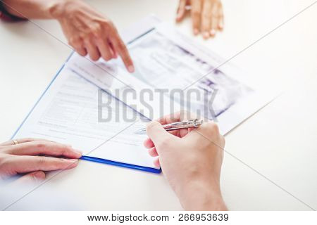 Dentist Consulting With Patient Presenting Results On Dental X-ray Film About The Problem Of The Pat