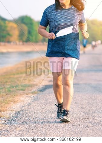 Sportive Woman Take Off Protective Mask While Jogging For Easier Breathing On Road Beside Irrigation