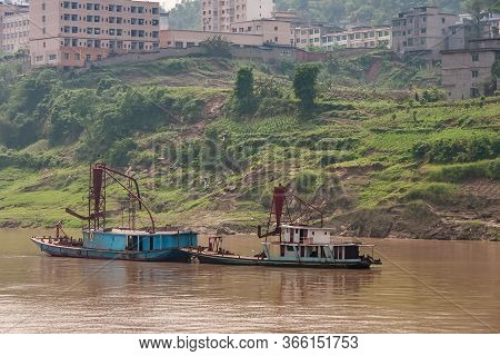 Fengdu, Chongqing, China - May 8, 2010: Yangtze River. Small Rusty Blue Dredging Boats On Brown Wate
