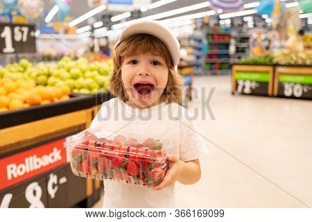 Excited American Kid With Shopping Trolley With In Grocery Store. Little Boy In The Supermarket Hold