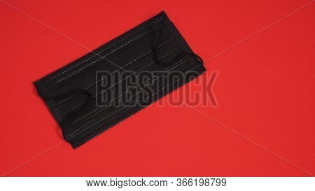 Black Disposable Ear- Loop Face Mask On Red Background.