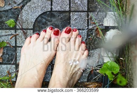Woman Feet With Red Nail Lacquer Washing With Water Pate On Garden Tale Background