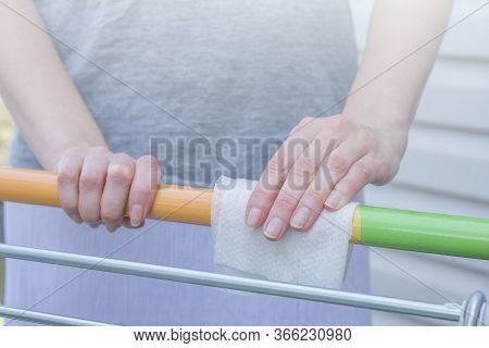 Viral Disease Prevention Concept. Woman Wipes Down A Handle Of Public Shopping Cart With A Disinfect