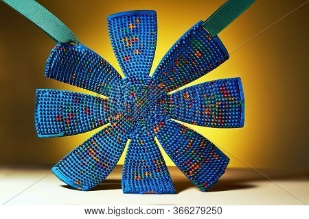 A Blue Massage Mat Shaped Like Chamomile In Hangs On Rubbers On A Yellow Background. Advertising And