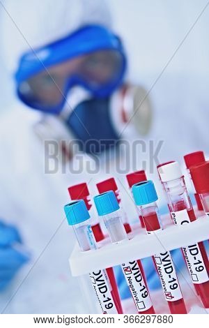 COVID-19. Doctor, microbiologist, scientist in a protective suit, makes a research on blood samples of infected people in the laboratory. Coronavirus test.