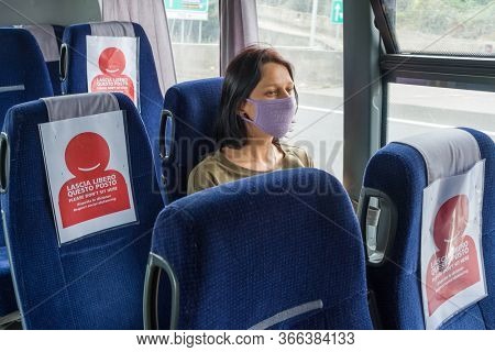 COVID-19 Public bus traveling during the coronavirus pandemic. Woman wearing protective mask while traveling by bus with new social distancing protect rules during pandemic of coronavirus in Italy