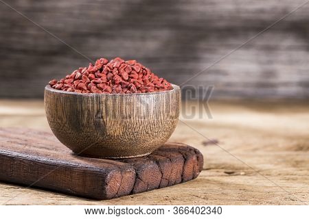 Annatto Seeds In Bowl On Wooden Background