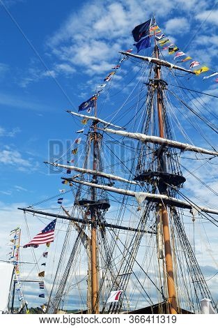 The Tall Mast Of A Big Tall Ship With All The Flags Under A Blue Sky With
Some White Clouts
