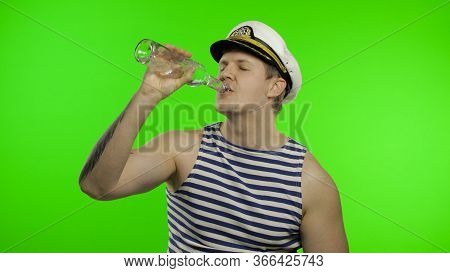 Young Drunk Muscular Sailor Man Drinks Vodka From Bottle. Seaman Guy Smiling In Sailors Vest. Stripe