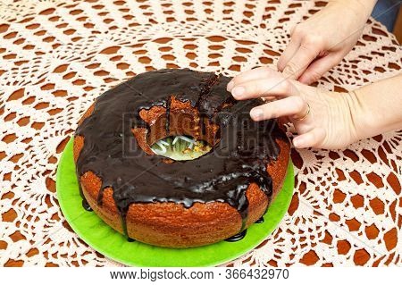 Hands Slicing Delicious And Healthy Traditional Brazilian Homemade Carrot Cake With Chocolate Sauce.