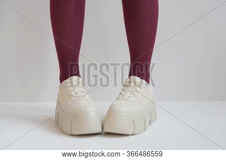 Long Slender Legs Close-up. Thick-soled Sneakers. Red Stockings Or Tights. Trend, Fashion, Trend