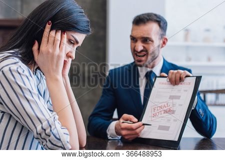 Selective Focus Of Stressed Woman And Angry Collector Pointing With Pen At Documents With Final Noti