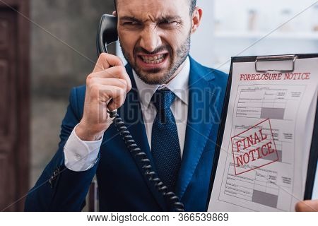 Angry Collector With Handset And Documents With Foreclosure And Final Notice Lettering In Room